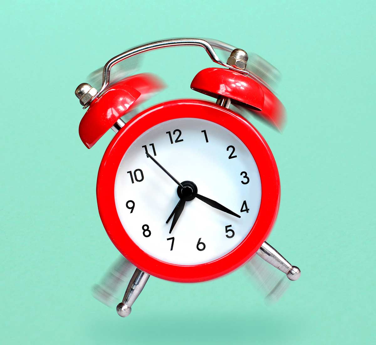 Bright red alarm clock with mint green backdrop