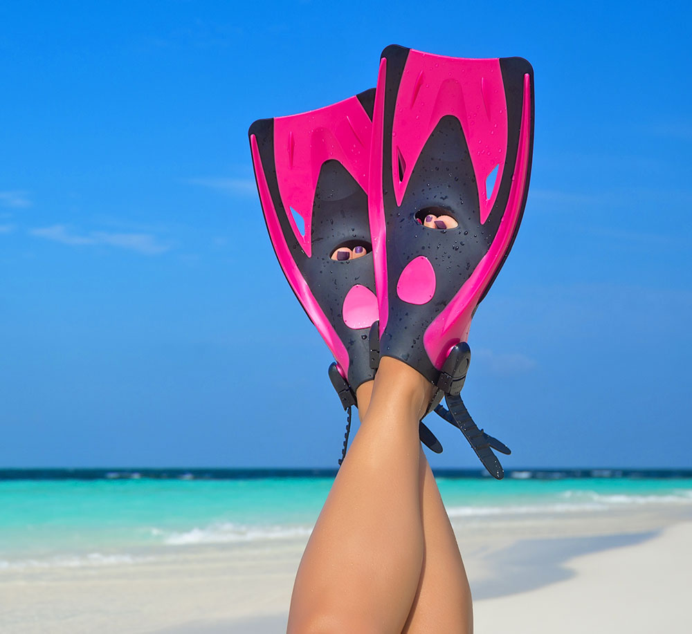 Woman lying upside down on beach with flippers