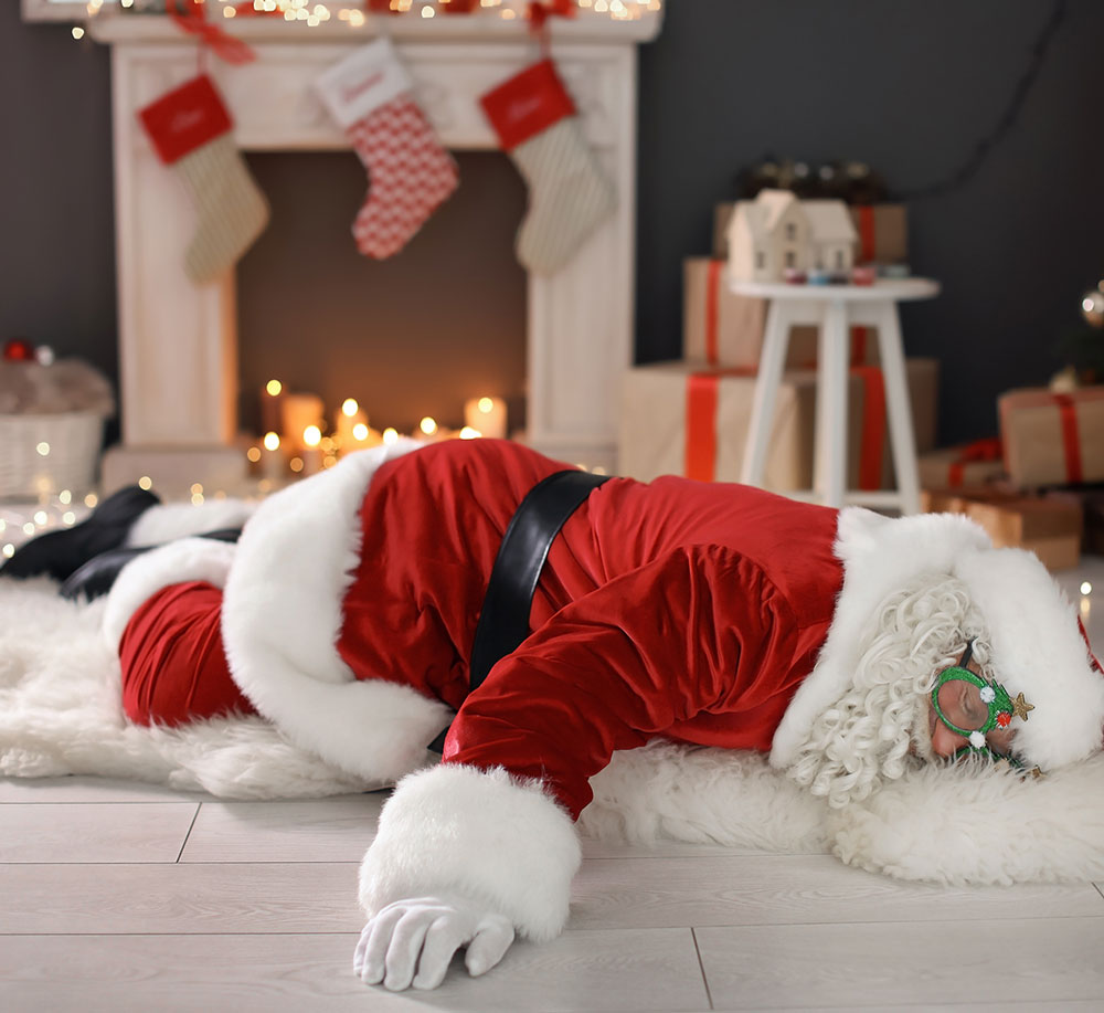 Tired Santa asleep in front of a fire